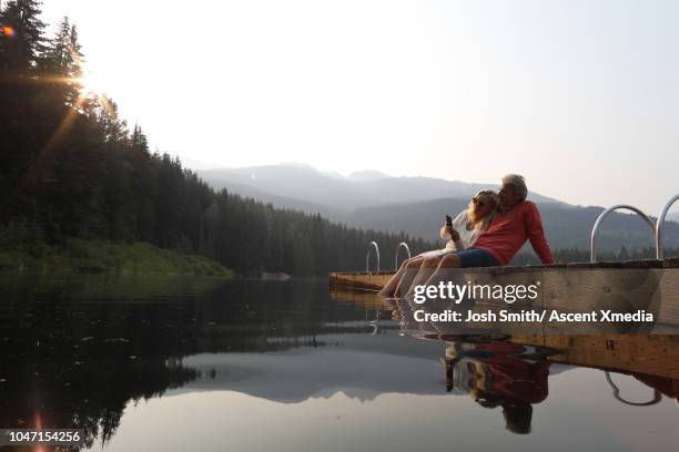 couple relax on wooden lake pier, at sunrise - travel memories stock pictures, royalty-free photos & images