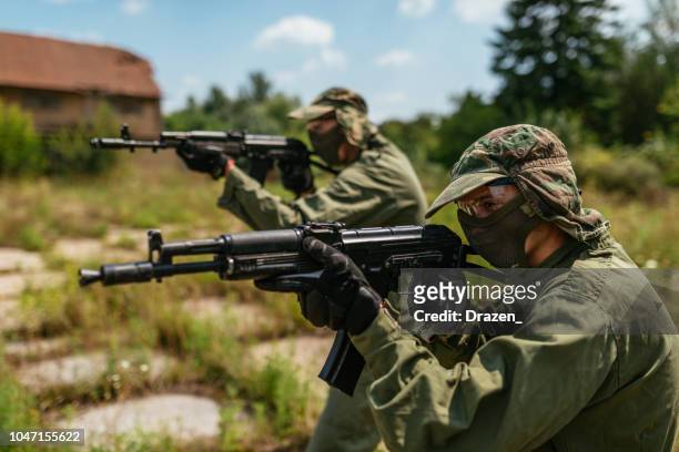 freunde spielen kriegsspiel mit airsoft-waffen - militant groups stock-fotos und bilder