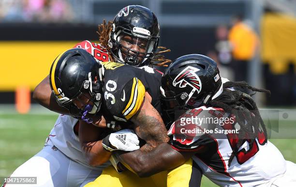 James Conner of the Pittsburgh Steelers is wrapped up for a tackle by Takkarist McKinley and De'Vondre Campbell of the Atlanta Falcons in the first...