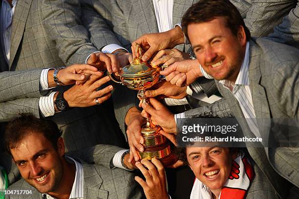 European Team members Edoardo Molinari, Rory McIlroy and Graeme McDowell pose with the Ryder Cup and their teammates following Europe's 14.5 to 13.5...