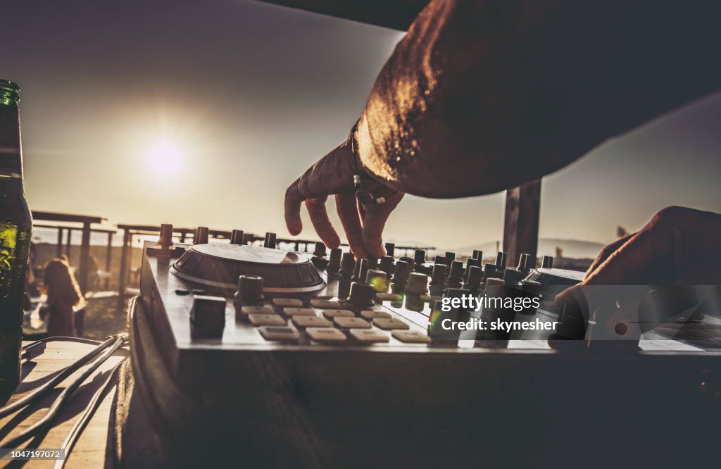 Close up van een DJ die muziek te spelen op het strand bij zonsondergang.