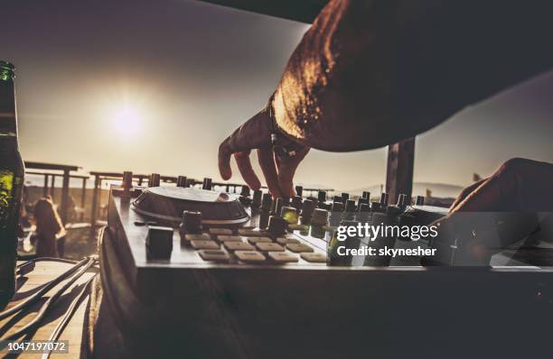 close up of a dj playing music on the beach at sunset. - beach music stock pictures, royalty-free photos & images