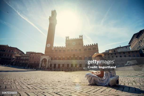 teenager-mädchen liest ein buch über die piazza del campo in siena, italien - siena stock-fotos und bilder