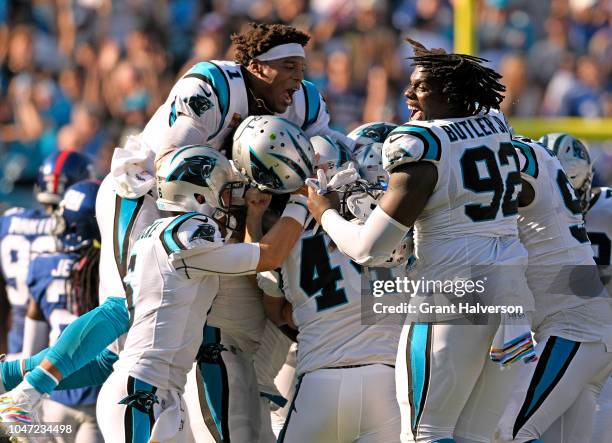 Cam Newton and teammates pile on Graham Gano of the Carolina Panthers after his game-winning 63-yard field goal against the New York Giants during...