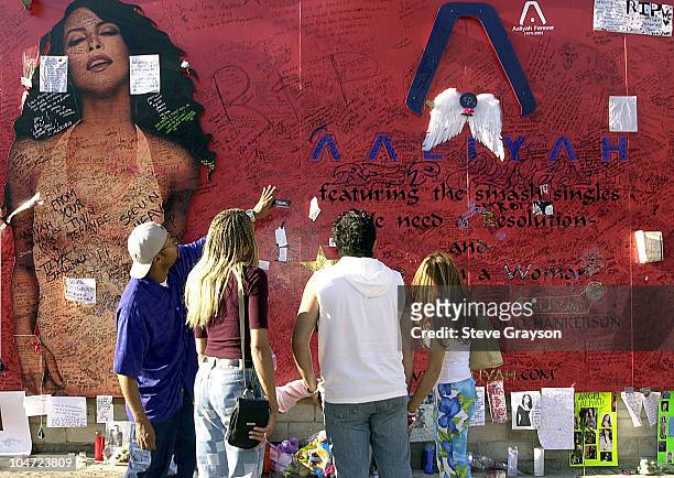 Fans of R&B singer/actress Aaliyah looks on at a record store mural of the late singer in what has become a shrine dedicated to her after her death...