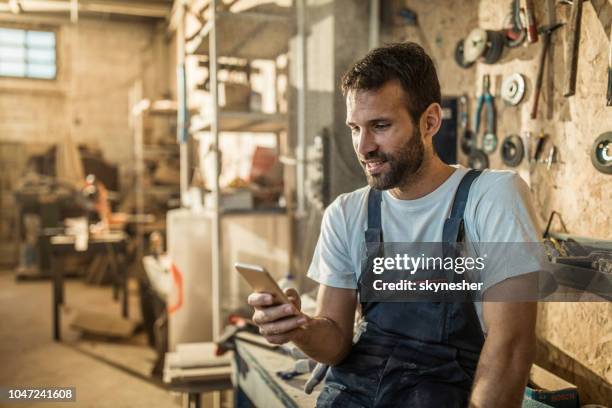 trabajador manual feliz con teléfono móvil en un taller. - carpintería fotografías e imágenes de stock