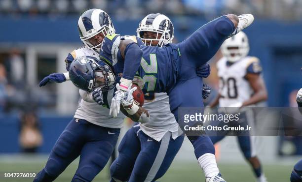 Running back Chris Carson of the Seattle Seahawks is tackled by linebacker Cory Littleton and defensive tackle Michael Brockers of the Los Angeles...