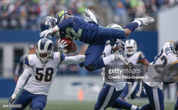 Running back Chris Carson of the Seattle Seahawks is tackled by linebacker Cory Littleton and defensive tackle Michael Brockers of the Los Angeles...