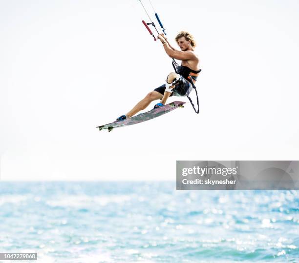 jeune homme volant avec kiteboard au-dessus de la mer. - kitesurf photos et images de collection