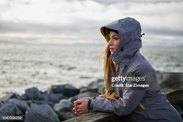 junge schöne frau mit regenjacke bei kaltem wetter - jacket stock-fotos und bilder