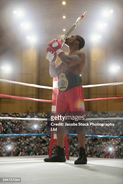 african american kissing trophy in boxing ring - championship ring stockfoto's en -beelden