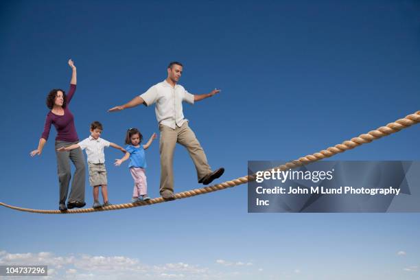 family walking across tightrope - suit photos et images de collection