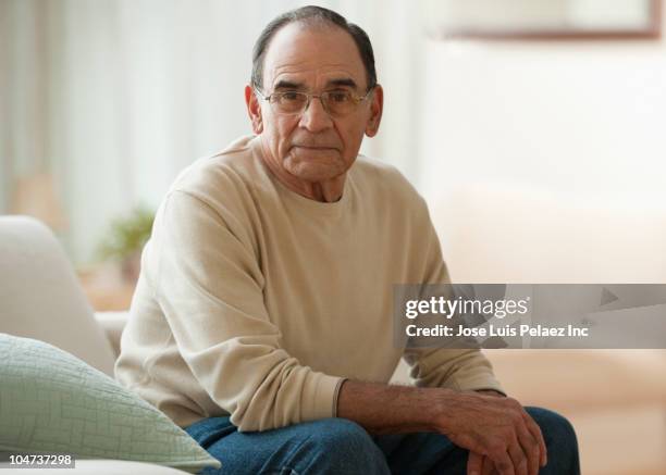 senior hispanic man sitting in living room - west new york new jersey stock-fotos und bilder