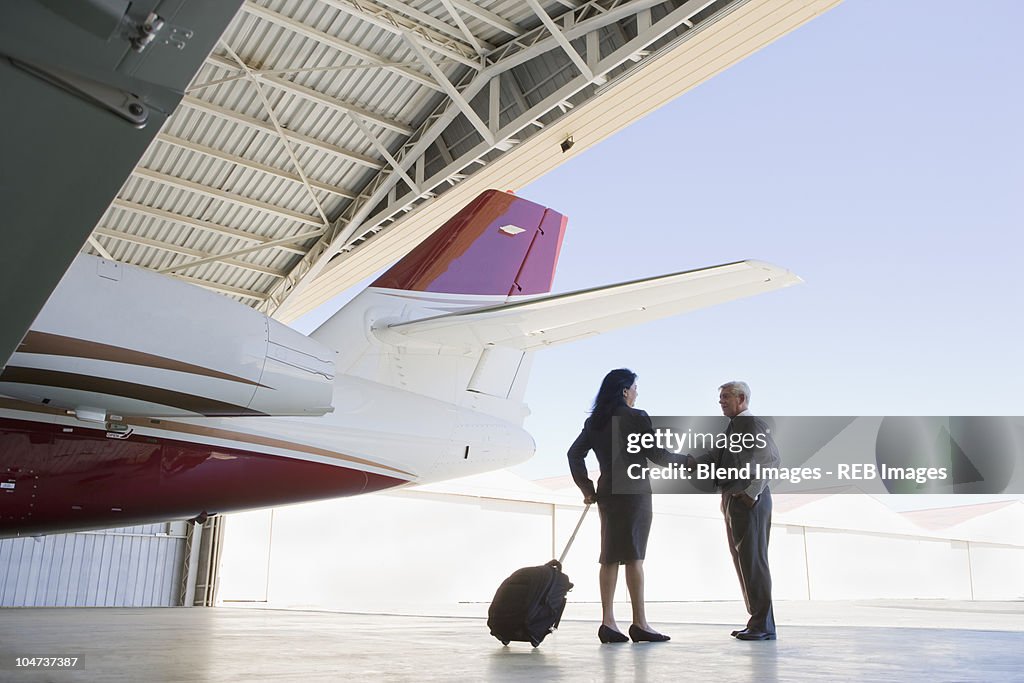 Hispanic business people meeting in airplane hangar