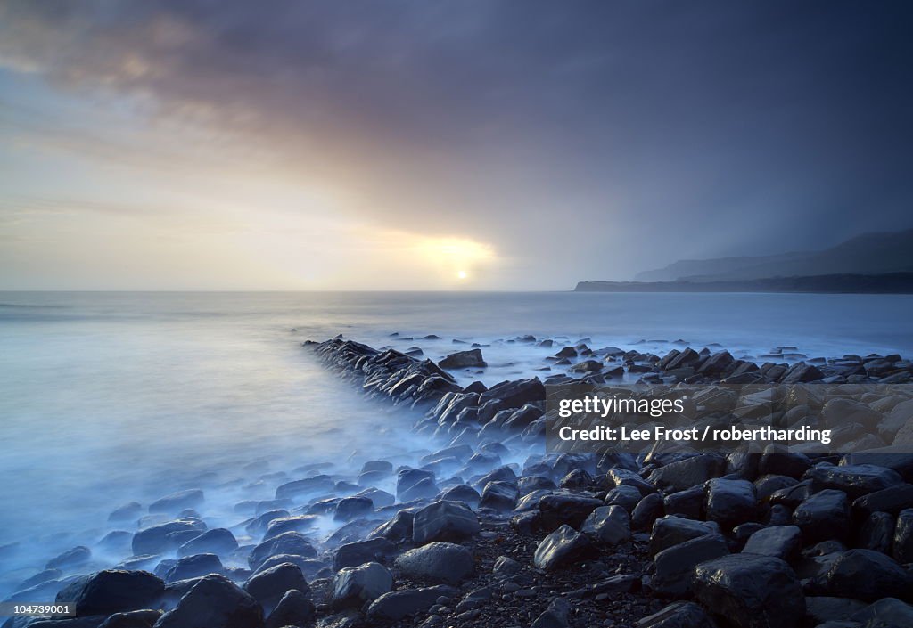 Sunset on a stormy winter's day looking across Kimmeridge Bay from the remains of Clavell's Pier, Kimmeridge, near Swanage, Dorset, England, United Kingdom, Europe