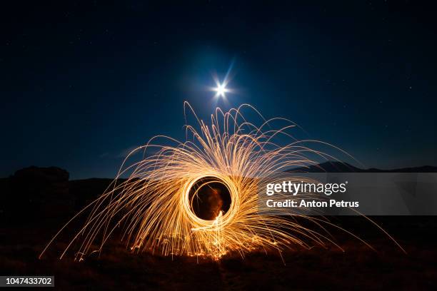 bright sparks at night in the mountains. fire show of steel wool - stunt person foto e immagini stock