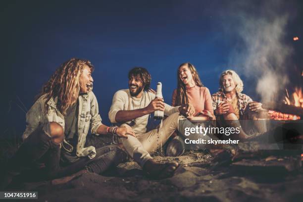 cheerful friends having fun by the campfire during the autumn night. - open fire stock pictures, royalty-free photos & images