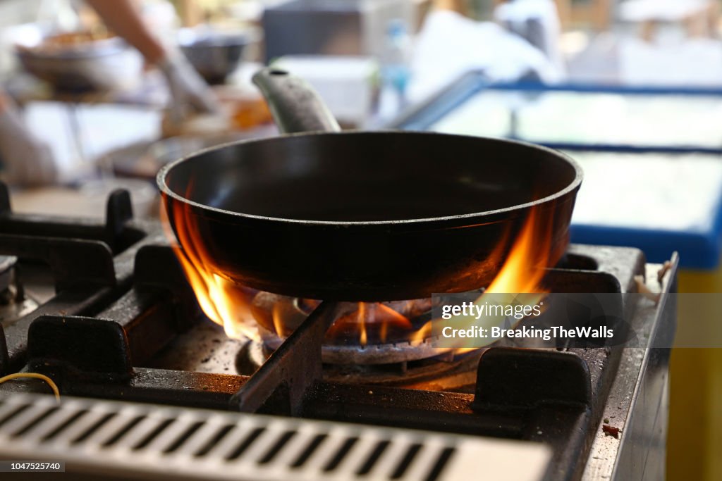 Close-Up Of Cooking Pan On Burning Stove At Restaurant