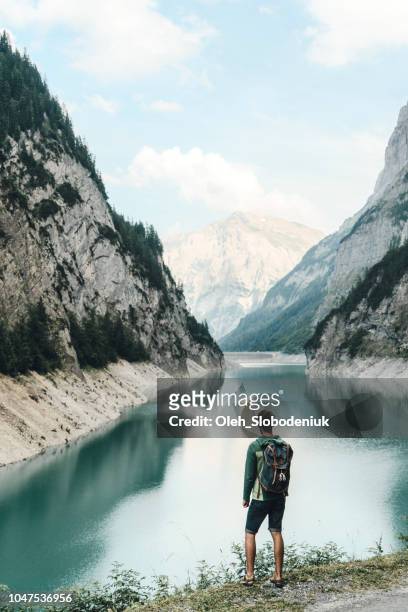 mann sucht am damm in schweizer alpen - wasserkraft stock-fotos und bilder