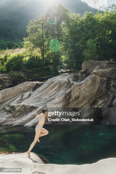 vista panorámica de mujer saltando de la roca cerca del río en lavertezzo - locarno fotografías e imágenes de stock