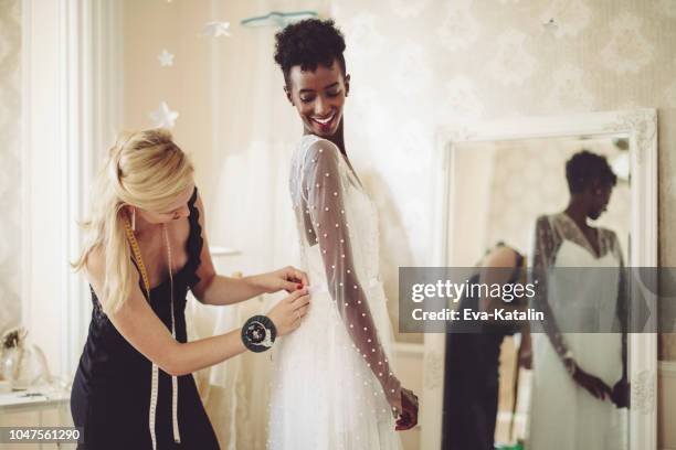 lo stilista sta regolando l'abito da sposa - african american wedding foto e immagini stock