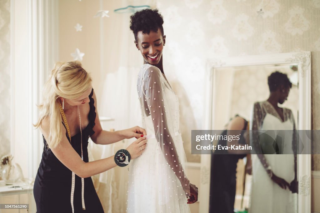 Fashion designer is adjusting the wedding dress