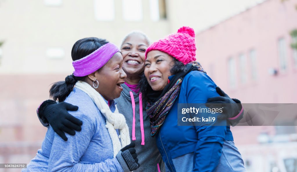 African-American women in city, laughing, hugging