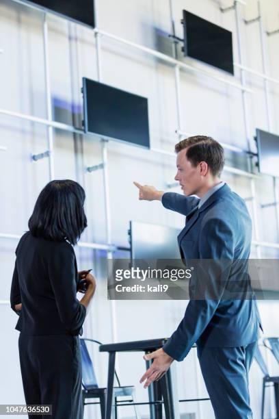 two multi-ethnic young business people looking, pointing - business woman pointing stock pictures, royalty-free photos & images