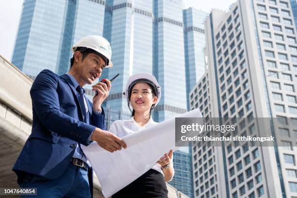 communication of engineer and secretary in construction site - business man overseeing blueprints outdoor stock-fotos und bilder