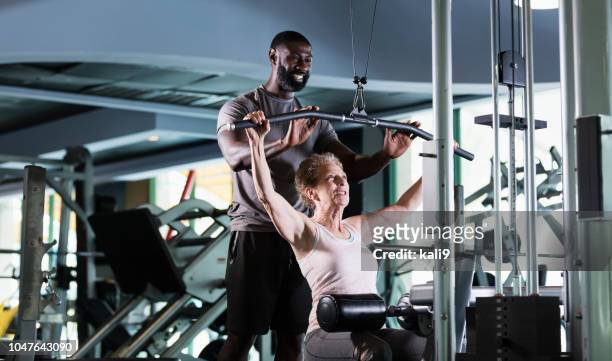 personal trainer helping senior woman at gym - personal training stock pictures, royalty-free photos & images