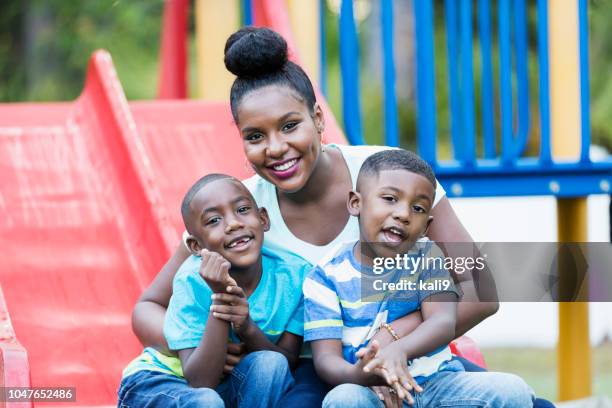 donna afroamericana con figli nel parco giochi - famiglia con due figli foto e immagini stock