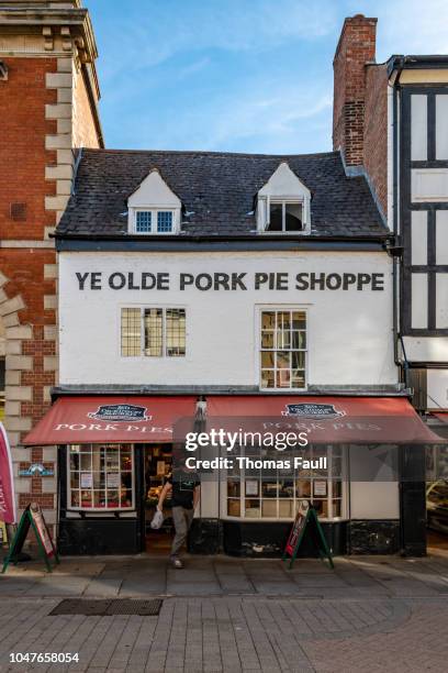 male shopper exits 'ye olde pork pie shoppe' in melton mowbray - awning stock pictures, royalty-free photos & images