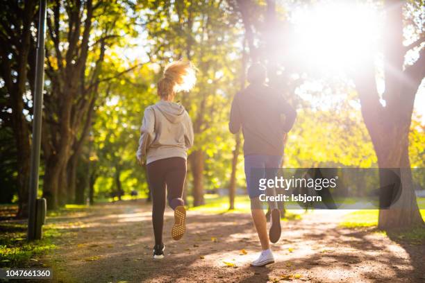 couple exercising in park. - jogging stock pictures, royalty-free photos & images