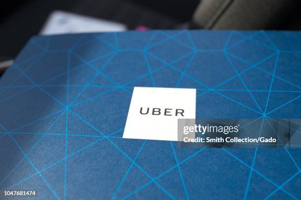 Close-up of logo for Uber on the blue printed background of a driver's manual issued to new drivers by the crowdsourced taxi service Uber, in an Uber...