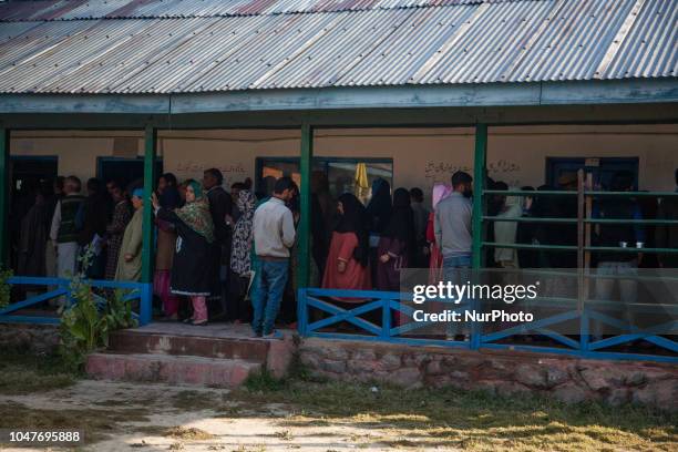 Kashmiris stand in queue to enter a polling station to cast their votes during the first phase of municipal polls, on October 8, 2018 in Srinagar,...