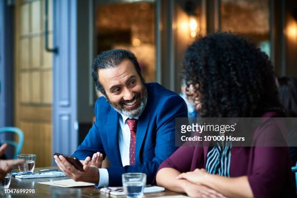 indian businessman with phone looking at colleague and smiling - lunch lady foto e immagini stock