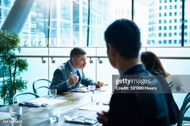 mature man talking to colleagues in modern office - obedience stock pictures, royalty-free photos & images