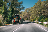 Tractor With Fertilizer Applicator With Tank In Motion On Country Road In Europe.