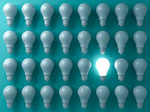 One glowing light bulb standing out from the unlit or dim bulbs on dark green pastel color background individuality and think different the business creative idea concepts 3D rendering