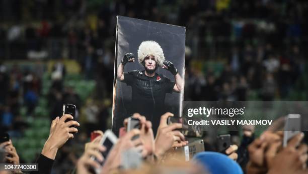 Fans hold a picture of UFC lightweight champion Khabib Nurmagomedov of Russia during a meeting upon the arrival at the Anzhi-arena stadium in...