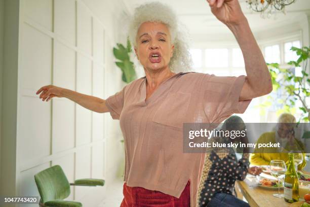 a carefree mature woman dancing at the dinner table - awkward dinner stock pictures, royalty-free photos & images