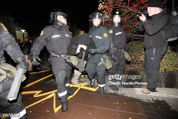 Riot police remove a protester from the grounds outside the Icelandic Parliament house as thousands of people are protesting the governments...