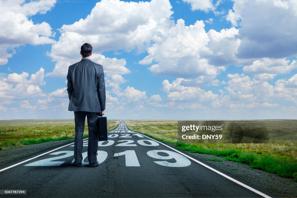 Businessman Stands On Long Road With Series Of Years Painted On It