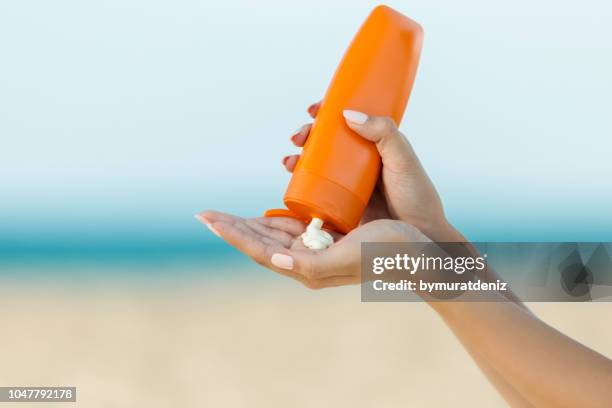 zonnebrandcrème van de toepassing van de vrouw de hand op het strand - gebruind stockfoto's en -beelden