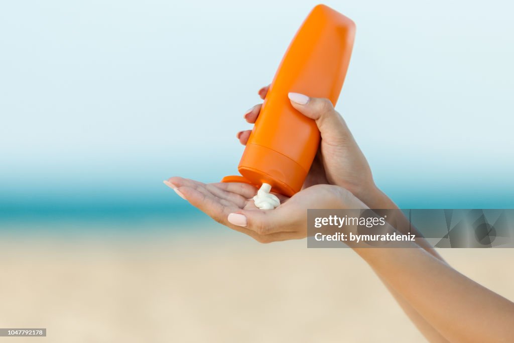 Woman hand apply sunscreen on the beach