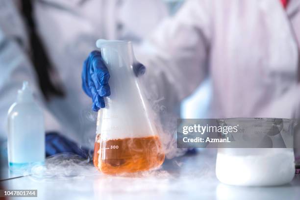 scienziato che tiene il pallone con liquido evaporante - reazione chimica foto e immagini stock