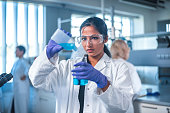 Female researcher pouring chemical into flask