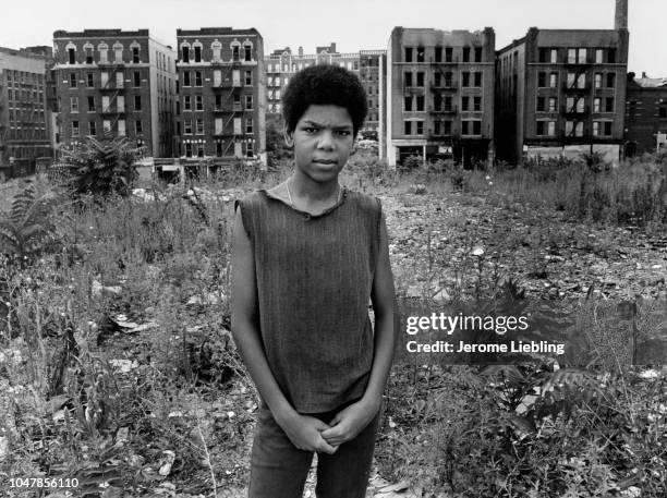 Portrait of an unidentified young man as he stands in a vacant lot near Charlotte Street in the South Bronx neighborhood, New York, New York, 1977....