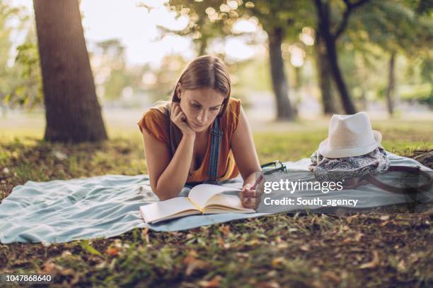 chica leyendo en el parque sola - mujer leyendo libro en el parque fotografías e imágenes de stock