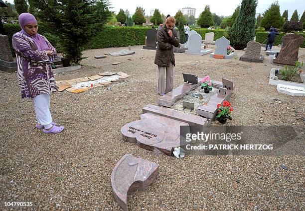 Two women look at a damaged gravestone in a cemetery where the Muslim section was desecrated by unknown vandals during the night, in the French...